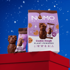 NOMO Cookie Dough plant-powered chocolate reindeer displayed on a red gift box against a blue snowy background. 